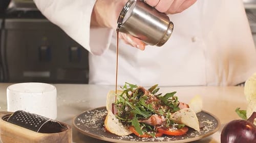Close Up Hand of Chef Pours Sauce Over a Vegetarian Seafood Salad