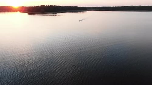 Aerial View of a Motor Fishing Boat Sailing on a Forest Lake at Sunset