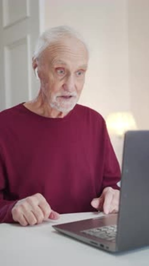 Senior Man Video Conferencing on Laptop at Home