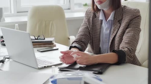 Businesswoman Sanitizing Hands in Office