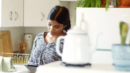 Frau benutzt digitales Tablet in der Küche