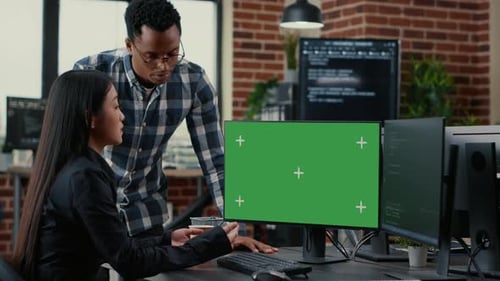 Equipe mista de programadores analisando o código-fonte olhando para a maquete de chroma key de tela verde