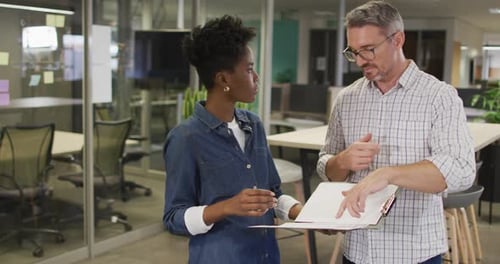 Coworkers Discussing Document in Modern Office