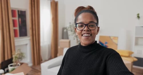 Smiling Woman Waving at Camera in Home