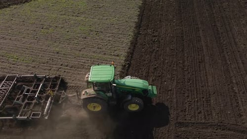 Traktor pflügt den Boden mit einem Pflug auf dem Feld
