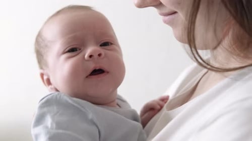 Loving Mother Holds Newborn Infant in Close Up