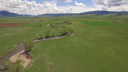 Aerial view flying over river winding through green valley
