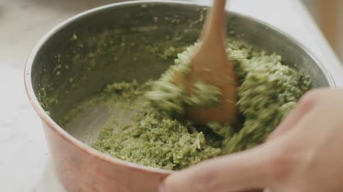 Crop woman mixing pesto sauce in bowl