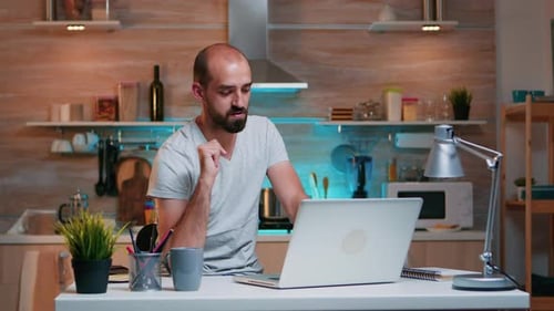 Man Working at Laptop in Kitchen