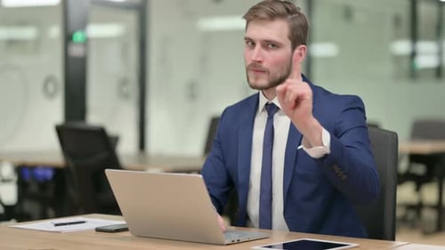 Man in Suit Works on Laptop, Points Finger
