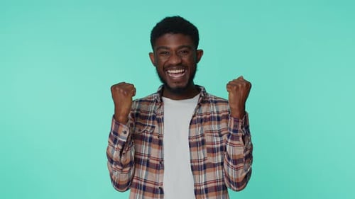 Afroamerikaner, der mit Geste die Fäuste hebt Ich habe es geschafft und den Erfolg gefeiert