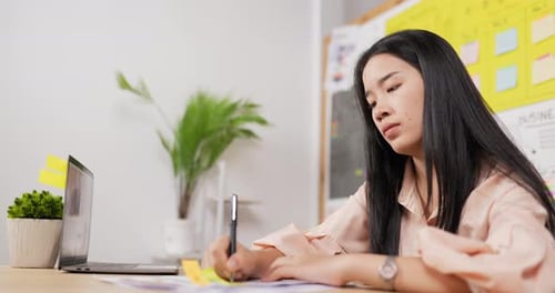 Young Woman Working at Desk Taking Notes