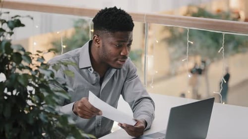 Man Reviews Documents and Gestures During Online Meeting