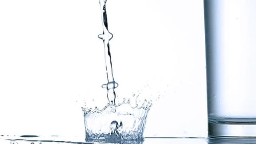 980002 Se vierte agua cerca del vidrio sobre un fondo blanco, Cámara lenta