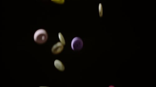 Colorful buttons falling and bouncing on black background, Ultra Slow Motion
