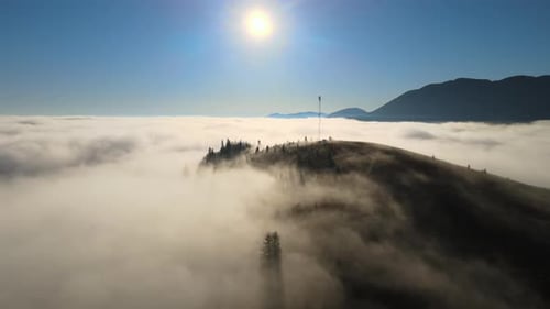 Aerial View of Colorful Sunrise Over White Dense Fog with Distant Dark Silhouettes of Mountain Hills