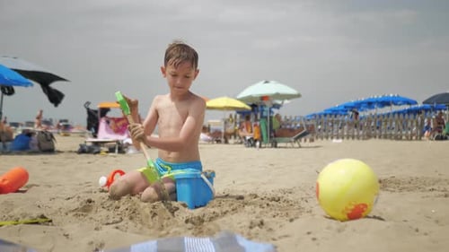 Boy Playing With Shovel on Sunny Beach