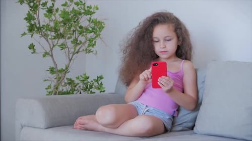 Girl with Curly Hair Using Smartphone on Couch