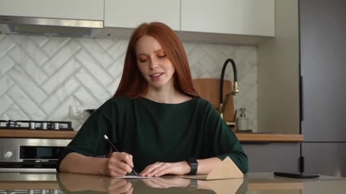Woman Writes and Seals Letter in Kitchen