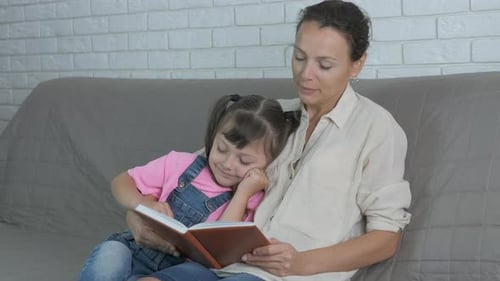 Mother Reading Book to Her Child on Couch