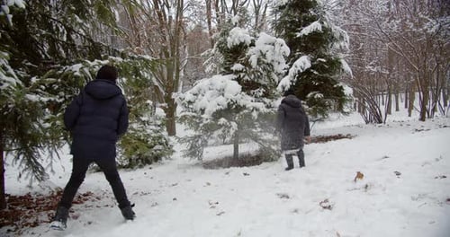 Glückliche Kinder, die Schneebälle in einem verschneiten Park spielen. Frohe Winterferien