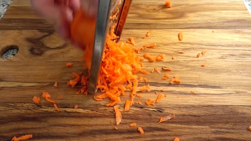 Person Grating a Carrot on Cutting Board
