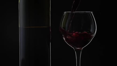 Rose Wine. Red Wine Pour in Wine Glass Over Black Background. Slow Motion
