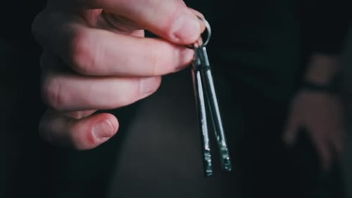 Hand Displaying Silver Keys on Dark Background