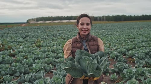 Smiling Woman Farmer Holding Cabbage in Field
