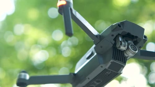 Helicóptero drone com hélices borradas e câmera de vídeo voando no ar.