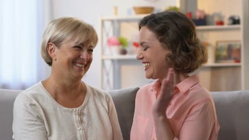 Two Women Laughing Together on Sofa Indoors