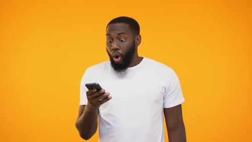 Surprised Man Looks at Smartphone in Studio