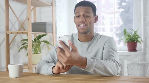 Smartphone Video Chat By Young AfroAmerican Man in Office