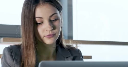 Concerned Woman Working on Laptop Computer and Looking Away Thinking Solving Problem at Office