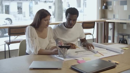Couple of Serious Young Designers Sitting at Table