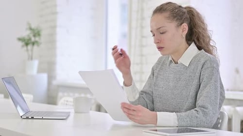 Woman Looks Shocked at Document Results in Office