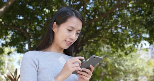 Woman Using Mobile Phone in Park Setting