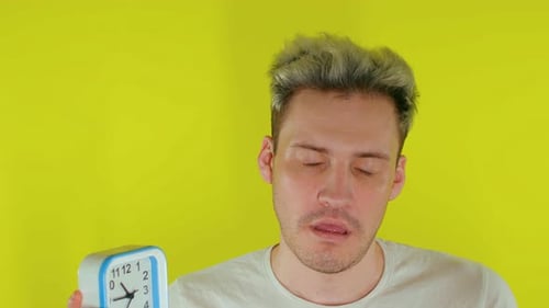 Close Up of Sleepy Man with Alarm Clock on Yellow Background