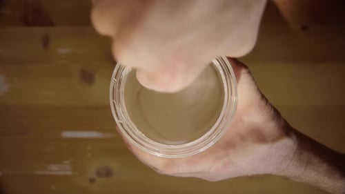 VERTICAL, TOP DOWN - Focus on jar rim, Sourdough starter is mixed, spoon lifted out