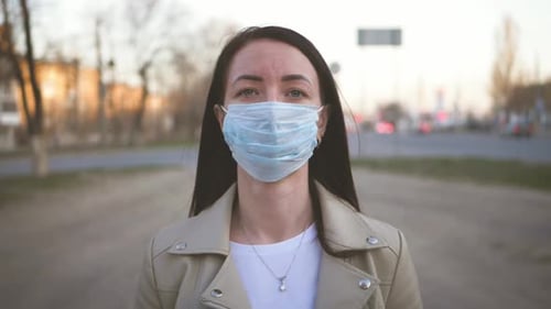 Young Woman in a Medical Mask for Protection From the Epidemic on the Street in the City. Concept