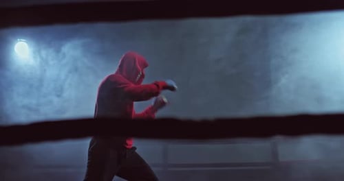Portrait Boxer Practicing Punches in the Ring Dark Gym with Tubers of Smoke