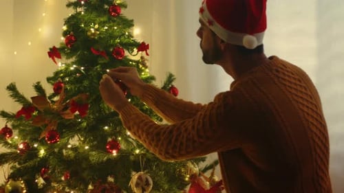 Young Man Decorating Christmas Tree with Ornaments