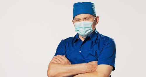 Serious Doctor with Blue Scrubs and Arms Crossed