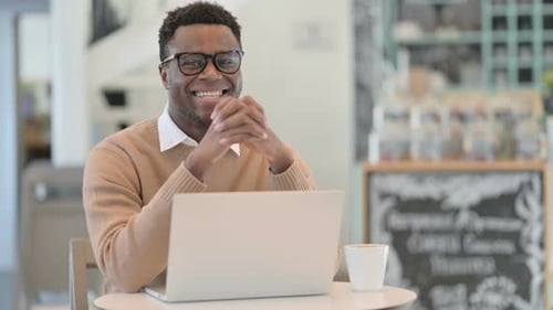 Smiling Man Using Laptop in Cafe