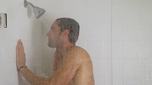 Man Taking Shower in Tiled Bathroom