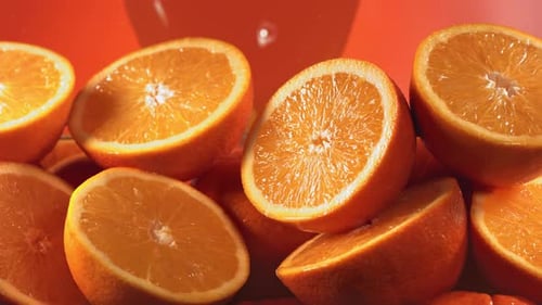 Cut Oranges Splashed with Juice on Orange Backdrop
