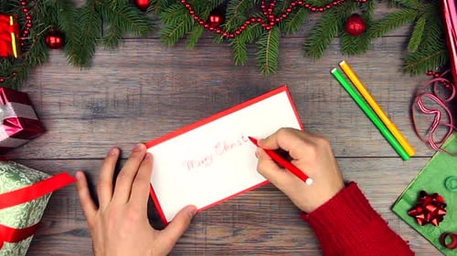 Man Writing "Merry Christmas" on Greeting Card