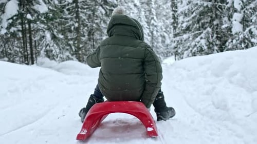 Kleiner Junge reitet im Winter Schlitten
