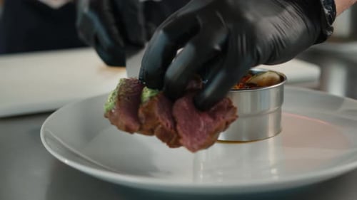 The chef puts filet mignon on a plate with ratatouille. Serving food in a restaurant.