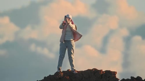 Glückliche Frau mit Smartphone online auf dem Hintergrund der Bergsonnenuntergangswolken
